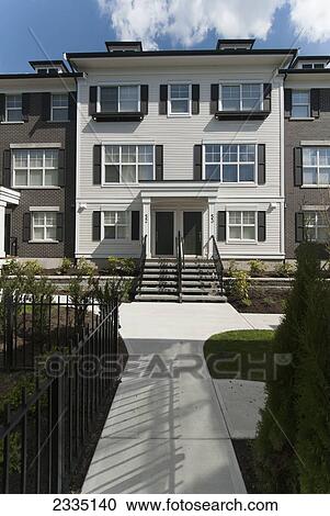 Stock Image - Modern Townhouse Row Exterior With Sidewalks And Porches; Surrey, British Columbia, Canada. Fotosearch