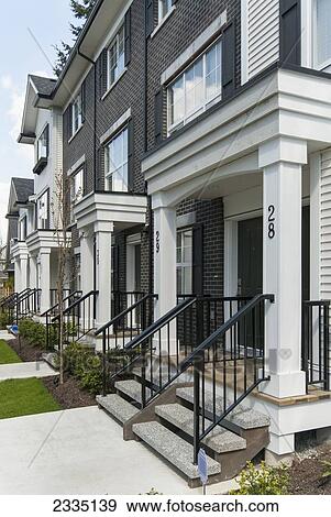 Stock Photo - Modern Townhouse Row Exterior With Sidewalks And Porches; Surrey, British Columbia, Canada. Fotosearch