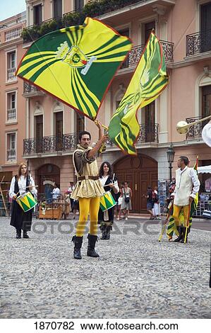 Stock Image - Monaco; Men And Women Dressed In Costumes And Waving Flags In The Street. Fotosearch