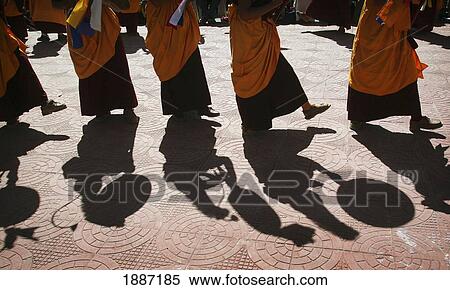 Stock Photography - Monks In Traditional Dress With Yellow Orange Hats And Robes Dancing And Banging Drums, Low Angle View. Fotosearch