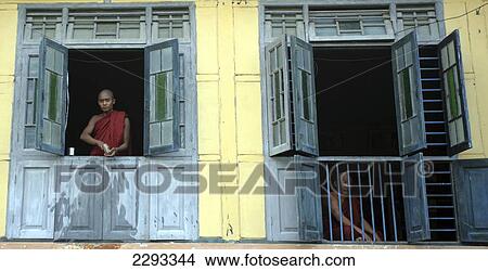 Picture - Monks sit looking out at Shew Paw Island Monastery on the banks of the Irrawaddy River; Myanmar. Fotosearch