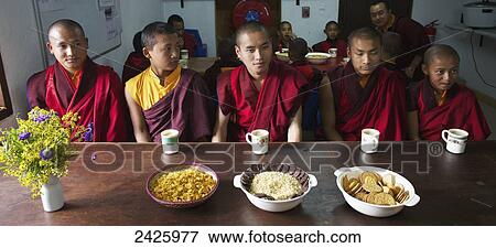 Stock Photo - Monks sitting at a table for mealtime at Gangteng Monastery; Phobjika Valley, Bhutan. Fotosearch