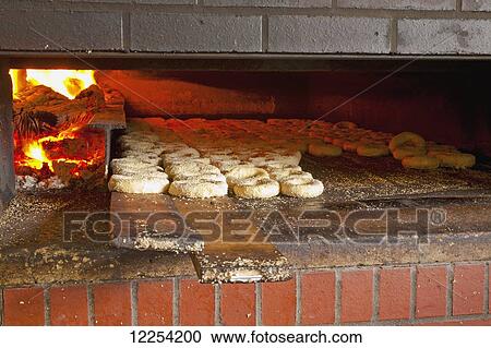 Stock Image - Montreal style bagels in wood fired oven; Magog, Quebec, Canada. Fotosearch
