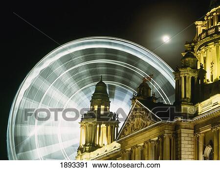 Stock Image - Moon Rising Behind Big Wheel And Belfast City Hall. Fotosearch
