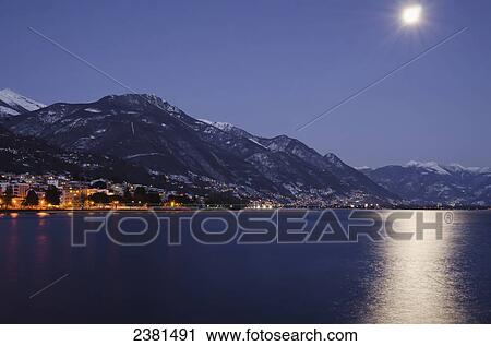 Moonlight reflecting on Lake Maggiore with buildings illuminated at nighttime along the shoreline; Locarno, Ticino, Switzerland View Large Photo Image Stock Image - Moonlight reflecting on Lake Maggiore with buildings illuminated at nighttime along the shoreline; Locarno, Ticino, Switzerland. Fotosearch