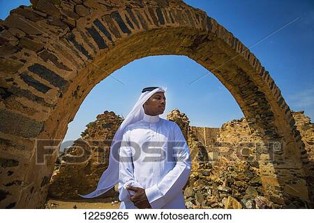 Stock Photography - Moor Saudi standing beneath arch of old building; Taif, Saudi Arabia. Fotosearch