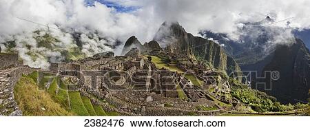 Stock Photograph - Morning fog and clouds reveal Machu Picchu, the ancient lost city of the Incas, one of Peru's top tourist destinations; Peru. Fotosearch