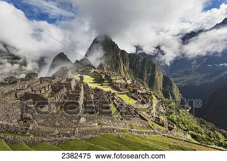Stock Photography - Morning fog and clouds reveal Machu Picchu, the ancient lost city of the Incas, one of Peru's top tourist destinations; Peru. Fotosearch