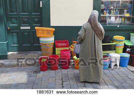 Moroccan Woman In Traditional Dress Looking At Plastic Goods On The Street Outside A Shop: Gibraltar Town, Gibraltar View Large Photo Image Stock Image - Moroccan Woman In Traditional Dress Looking At Plastic Goods On The Street Outside A Shop: Gibraltar Town, Gibraltar. Fotosearch