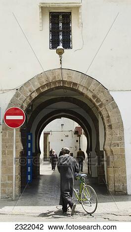 Stock Image - Morocco, Casablanca, Bike rider walking through Quartier Habbous. Fotosearch