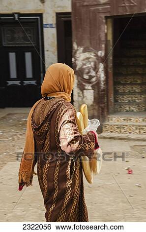 Morocco, Casablanca, Old Medina, Woman walking street carrying fresh bread View Large Photo Image Stock Photograph - Morocco, Casablanca, Old Medina, Woman walking street carrying fresh bread. Fotosearch