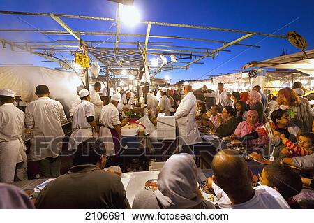Stock Image - Morocco, Cook serving food at stall in Djemaa el-Fna Square; Marrakech. Fotosearch