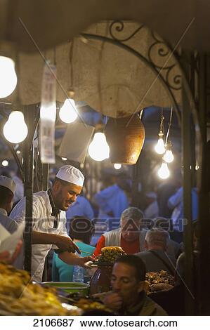 Stock Photo - Morocco, Cook serving food at stall in Djemaa el-Fna Square; Marrakech. Fotosearch