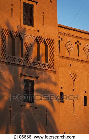 Stock Photograph - Morocco, Date palm shadow on wall of main kasbah of Dar Ahlam Hotel at dusk; Skoura. Fotosearch