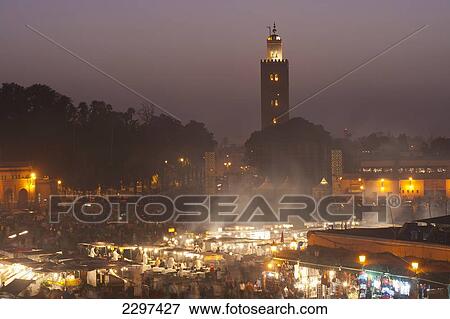 Morocco, Looking across food stalls in Dejmaa el Fna at dusk with minaret of Koutoubia mosque behind; Marrakesh View Large Photo Image Stock Photo - Morocco, Looking across food stalls in Dejmaa el Fna at dusk with minaret of Koutoubia mosque behind; Marrakesh. Fotosearch