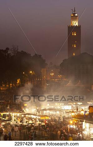 Stock Photo - Morocco, Looking across food stalls in Dejmaa el Fna at dusk with minaret of Koutoubia mosque behind; Marrakesh. Fotosearch