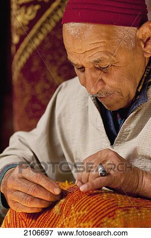 Stock Photo - Morocco, Man fixing carpet; Marrakech. Fotosearch