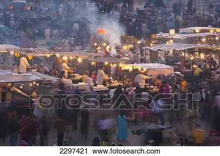 Stock Image - Morocco, People and food stalls in Place Djemaa el Fna at dusk; Marrakesh. Fotosearch