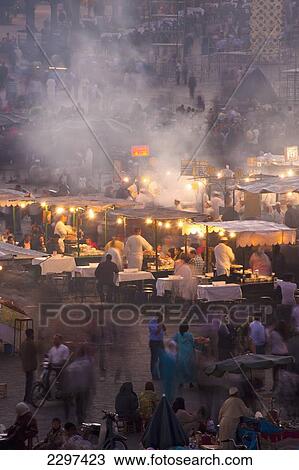 Stock Image - Morocco, People and food stalls in Place Djemaa el Fna at dusk; Marrakesh. Fotosearch