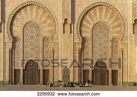 Stock Image - Morocco, People in front of massive doors to Hassan II Mosque at dusk; Casablanca. Fotosearch
