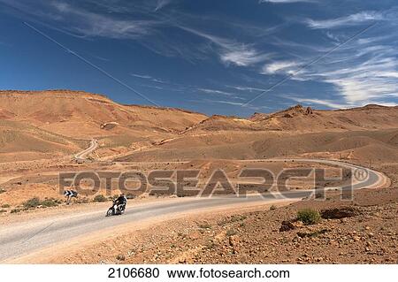 Stock Image - Morocco, Two men motorbike driving through desolate scenery; Valley of Roses. Fotosearch