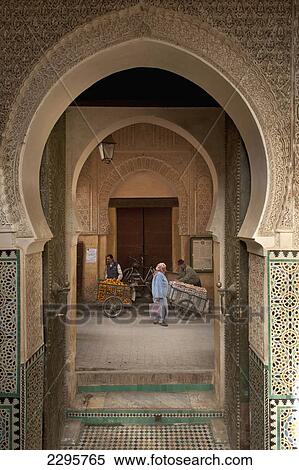 Morocco, Woman walking past orange and egg sellers outside entrance to Medersa Bou Inania; Fez View Large Photo Image Stock Photography - Morocco, Woman walking past orange and egg sellers outside entrance to Medersa Bou Inania; Fez. Fotosearch