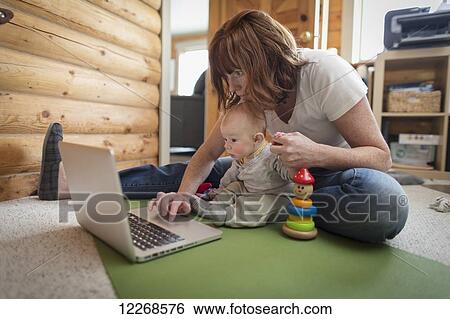 Mother and baby sitting in front of a laptop on the floor of a cabin, Homer, Southcentral Alaska View Large Photo Image Stock Photograph - Mother and baby sitting in front of a laptop on the floor of a cabin, Homer, Southcentral Alaska. Fotosearch