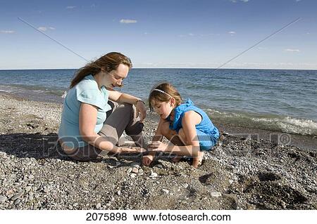 Mother And Daughter Collecting Stones By The Shoreline Of Lake Ontario; Ontario Canada View Large Photo Image Stock Photo - Mother And Daughter Collecting Stones By The Shoreline Of Lake Ontario; Ontario Canada. Fotosearch