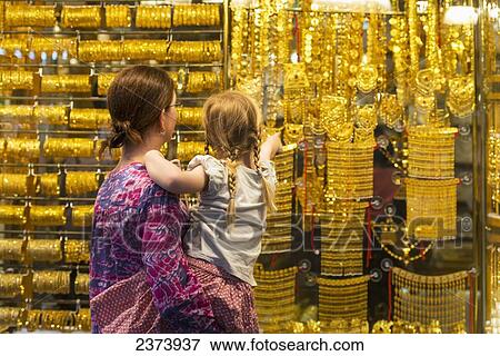 Mother and daughter looking at gold jewellery for sale in window of shop in the gold souk; Dubai, United Arab Emirates View Large Photo Image Stock Photo - Mother and daughter looking at gold jewellery for sale in window of shop in the gold souk; Dubai, United Arab Emirates. Fotosearch