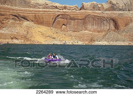 Stock Photo - Mother and daughter ride on purple towable tube behind speedboat on lake powell; page arizona usa. Fotosearch