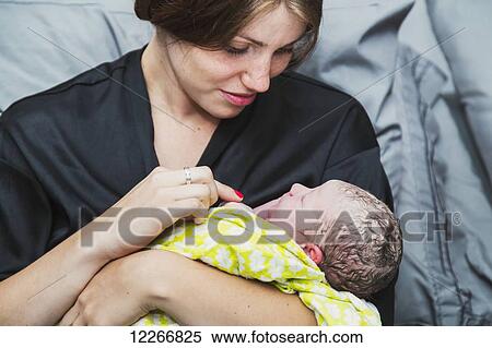 Stock Photography - Mother holding newborn baby girl in delivery room; Edmonton, Alberta, Canada. Fotosearch