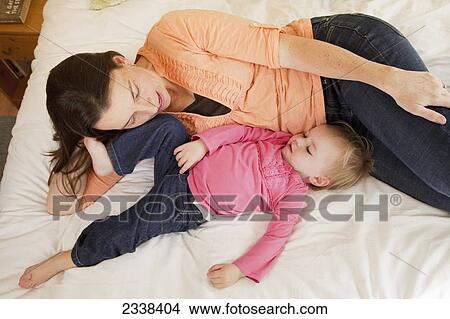 Mother Lying With Her Child Across A Bed; Oakland, California, Usa View Large Photo Image Picture - Mother Lying With Her Child Across A Bed; Oakland, California, Usa. Fotosearch