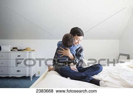 Stock Photo - Mother on a bed hugging her down syndrome child; Victoria, Vancouver Island, British Columbia, Canada. Fotosearch
