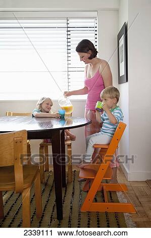 Stock Image - Mother Pouring Juice For Her Children; San Francisco, California, Canada. Fotosearch