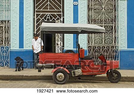 Stock Image - Motor Tricycle Beside Building With Decorative Grates, Camaguey, Cuba. Fotosearch