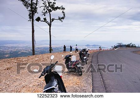 Stock Image - Motorbikes parked along the road in Preah Monivong National Park, just outside of Kampot; Cambodia. Fotosearch