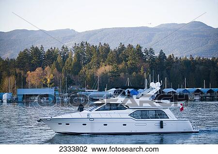 Stock Image - Motorboat Sailing Out Of Harbor, Vancouver Waterfront; Vancouver, British Columbia, Canada. Fotosearch