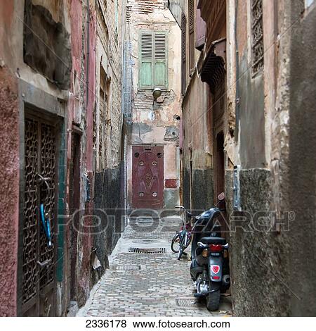 Motorcycle And Bicycle Parked In A Narrow Alley Outside Doorways; Marrakesh, Marrakech-Tensift-El Haouz, Morocco View Large Photo Image Stock Photo - Motorcycle And Bicycle Parked In A Narrow Alley Outside Doorways; Marrakesh, Marrakech-Tensift-El Haouz, Morocco. Fotosearch