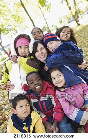 Stock Photography - Multi-Ethnic New Canadian Children Hug Their Teacher Outside Esl School; Guelph Ontario Canada. Fotosearch