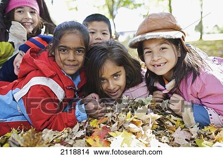 Picture - Multi-Ethnic New Canadian Children Playing In Autumn Leaves Outside Esl School; Guelph Ontario Canada. Fotosearch