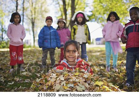 Stock Photo - Multi-Ethnic New Canadian Children Playing In Autumn Leaves Outside Esl School; Guelph Ontario Canada. Fotosearch