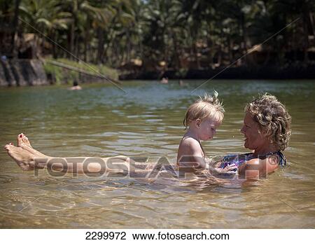 Mum and daughter enjoy swiming in the shallow fresh waters of the lagoon on Cola beach, Goa, India. View Large Photo Image Stock Image - Mum and daughter enjoy swiming in the shallow fresh waters of the lagoon on Cola beach, Goa, India.. Fotosearch