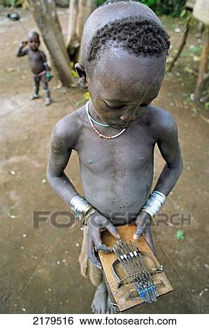 Mursi tribal boy playing a 'chongku'. Makki / South Omo / Southern Nations, Nationalities & People's Region (Ethiopia). View Large Photo Image Stock Photograph - Mursi tribal boy playing a 'chongku'. Makki / South Omo / Southern Nations, Nationalities & People's Region (Ethiopia).. Fotosearch