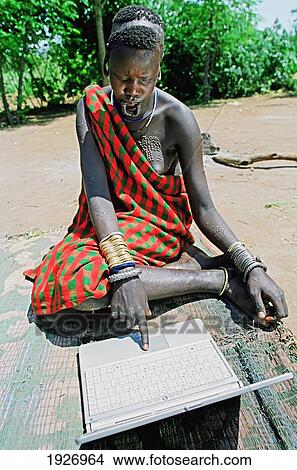 Picture - Mursi Tribal Girl With Piercedlower Lip Learning How To Use The Tribe's First Laptop. Fotosearch