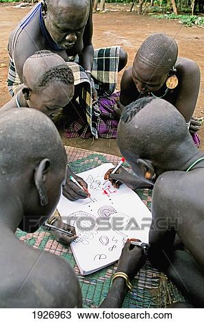Stock Image - Mursi Tribal People Drawing Traditional Patterns Using Western Visitor's Pad And Markers. Fotosearch