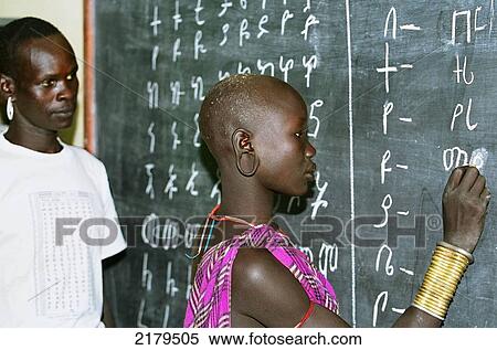 Stock Photography - Mursi tribal teacher & pupil during a Mursi Language lesson (written with Amharic Alphabet) in a school run by Christian missionaries (Serving in Mission). Makki / South Omo / Southern Nations, Nationalities & People's Region (Ethiopia).. Fotosearch