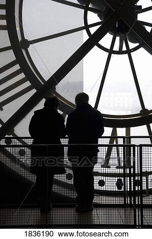 Stock Image - Musee D'orsay, Paris, France; Two People In Front Of Large Clock In Parisian Art Museum. Fotosearch