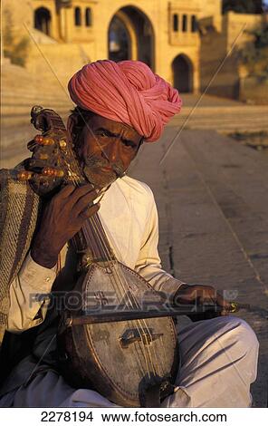 Picture - Musician playing traditional stringed instrument, Gadi Sagar Tank; Jaisalmer, India. Fotosearch