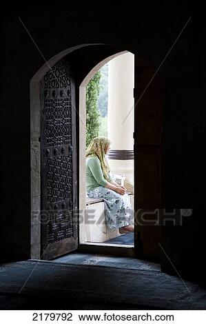 Stock Image - Muslim woman sitting in doorway of a mosque; Mostar, Bosnia and Herzegovina. Fotosearch