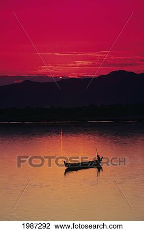 Myanmar (Burma), Bagan, Irrawaddy River, Fisherman In Boat Silhouetted Against Bright Red Sunset. View Large Photo Image Stock Image - Myanmar (Burma), Bagan, Irrawaddy River, Fisherman In Boat Silhouetted Against Bright Red Sunset.. Fotosearch